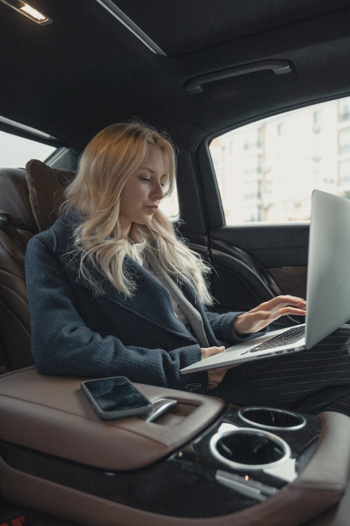 Services Businesswoman working remotely on a laptop in the backseat of a luxury car. Stylish, modern, and focused.